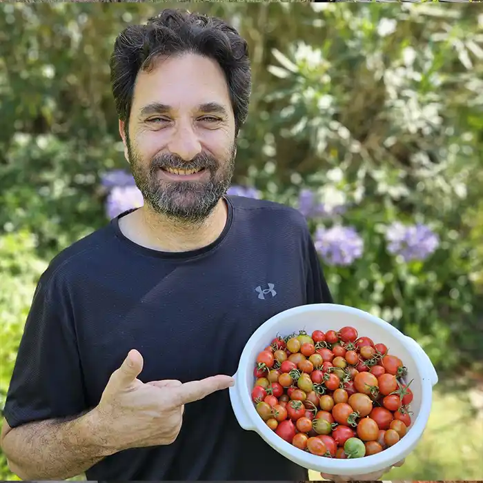Gabriel mostrando una cosecha de tomates cherry en su huerta